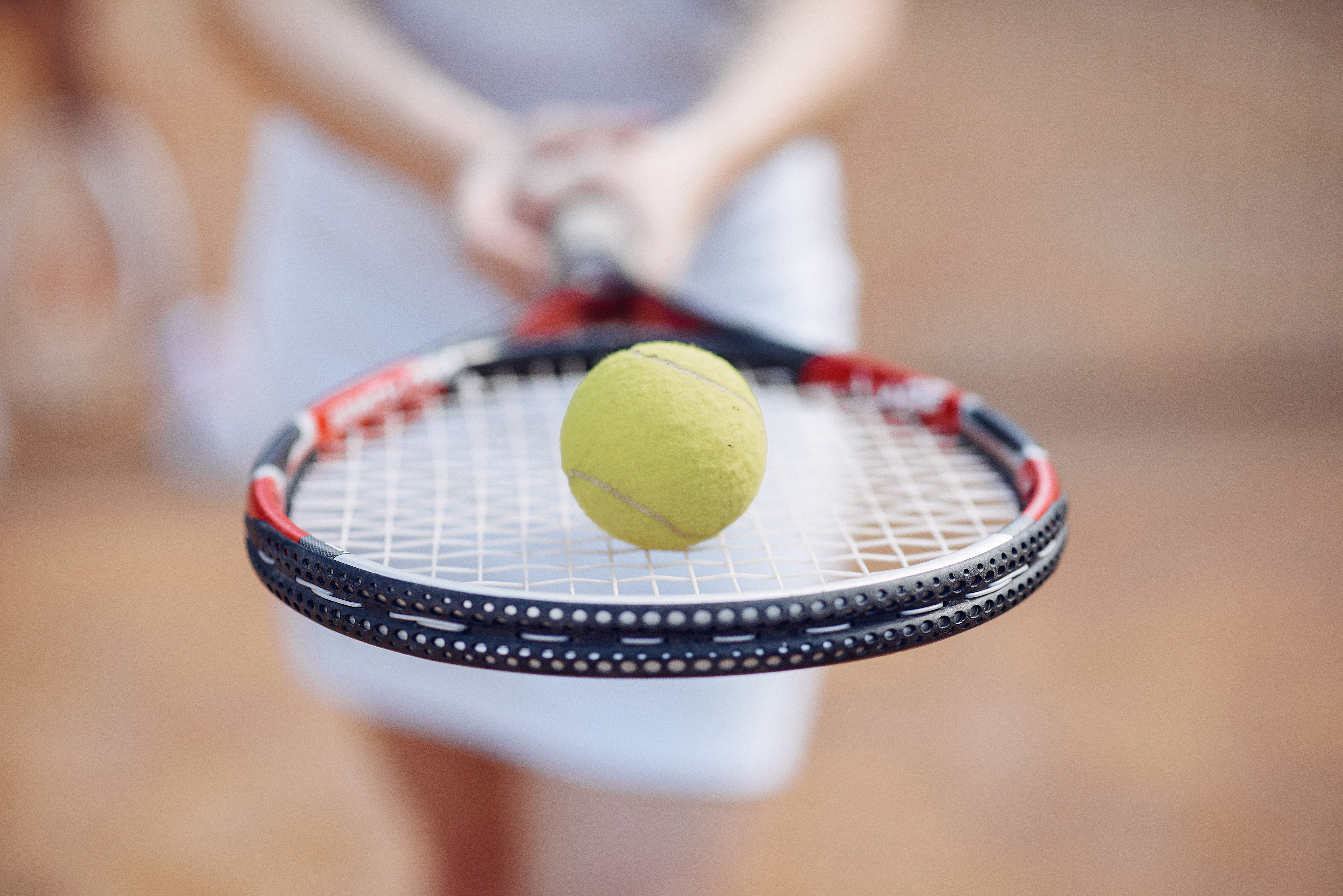 Focus on a racket with a tennis ball in the tennis club