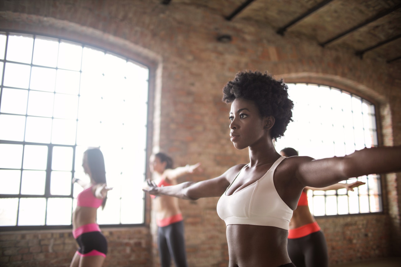 Confident fit ethnic woman training with other sportswomen to grow dance studio